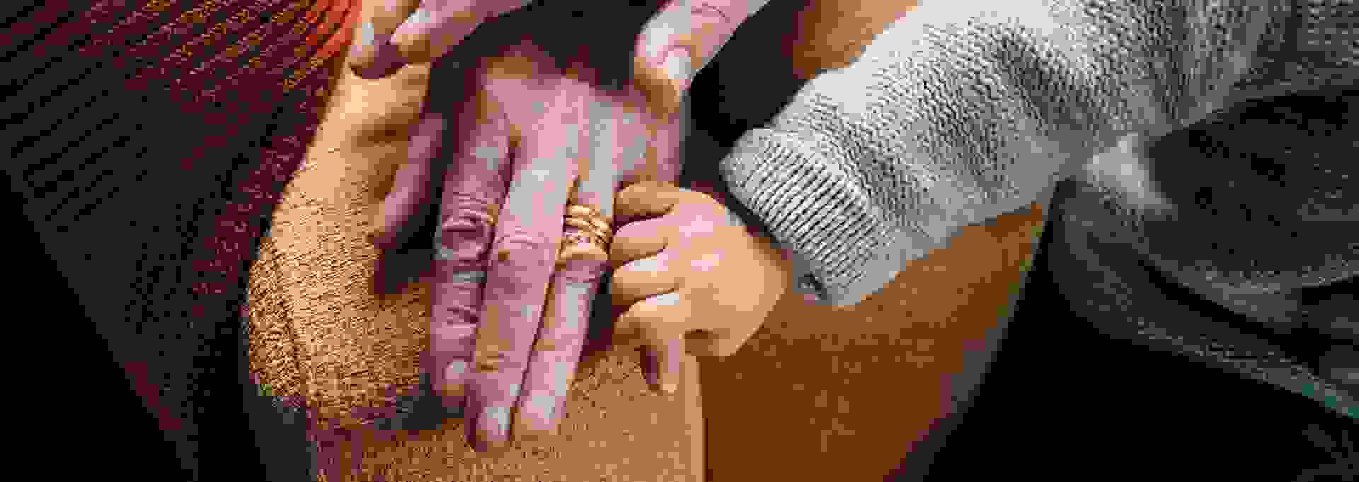 Pienen lapsen käsi iäkkään henkilön kädessä.
