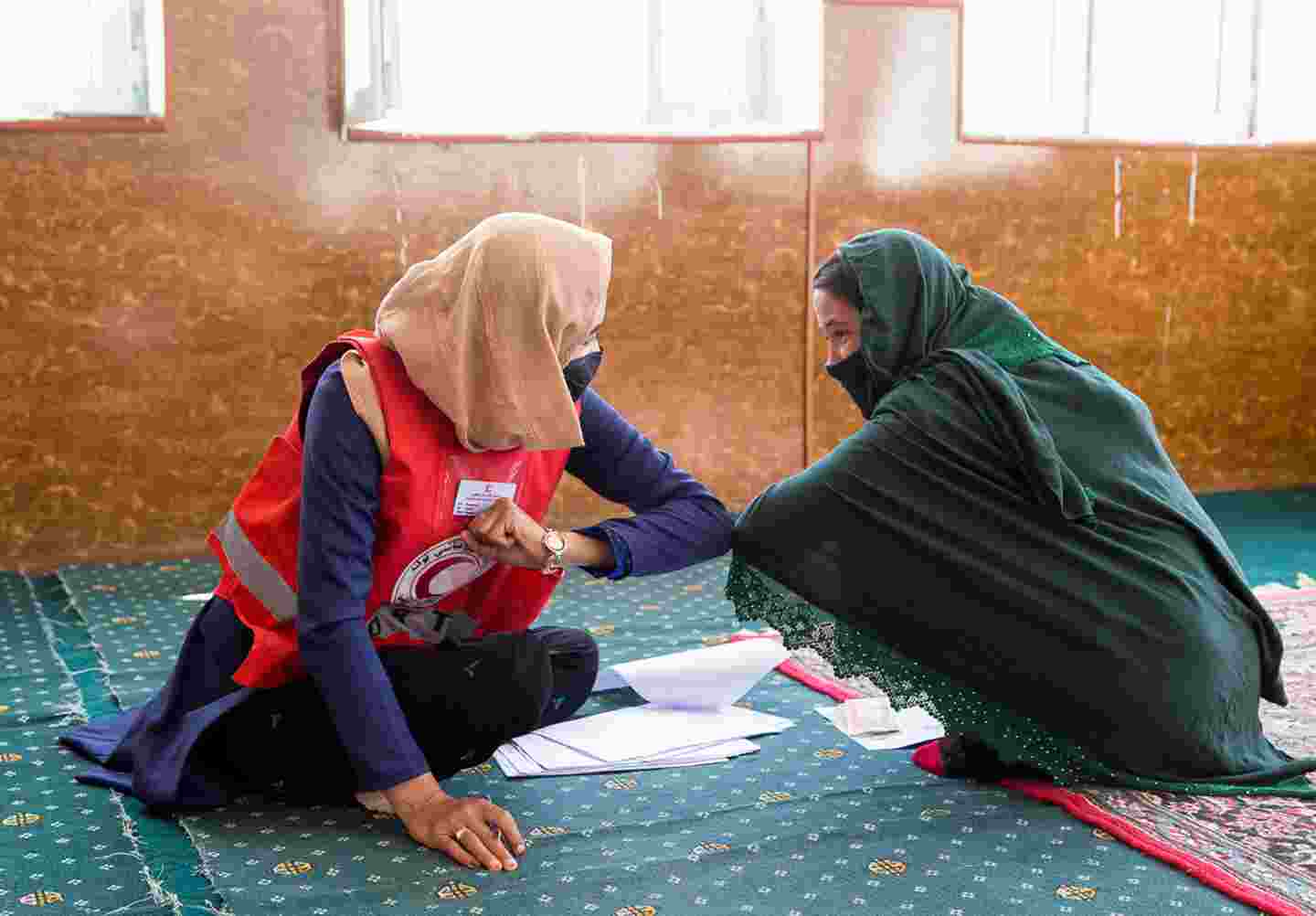 Punaisen Ristin vapaaehtoinen tervehtii toista naista Afganistanissa.