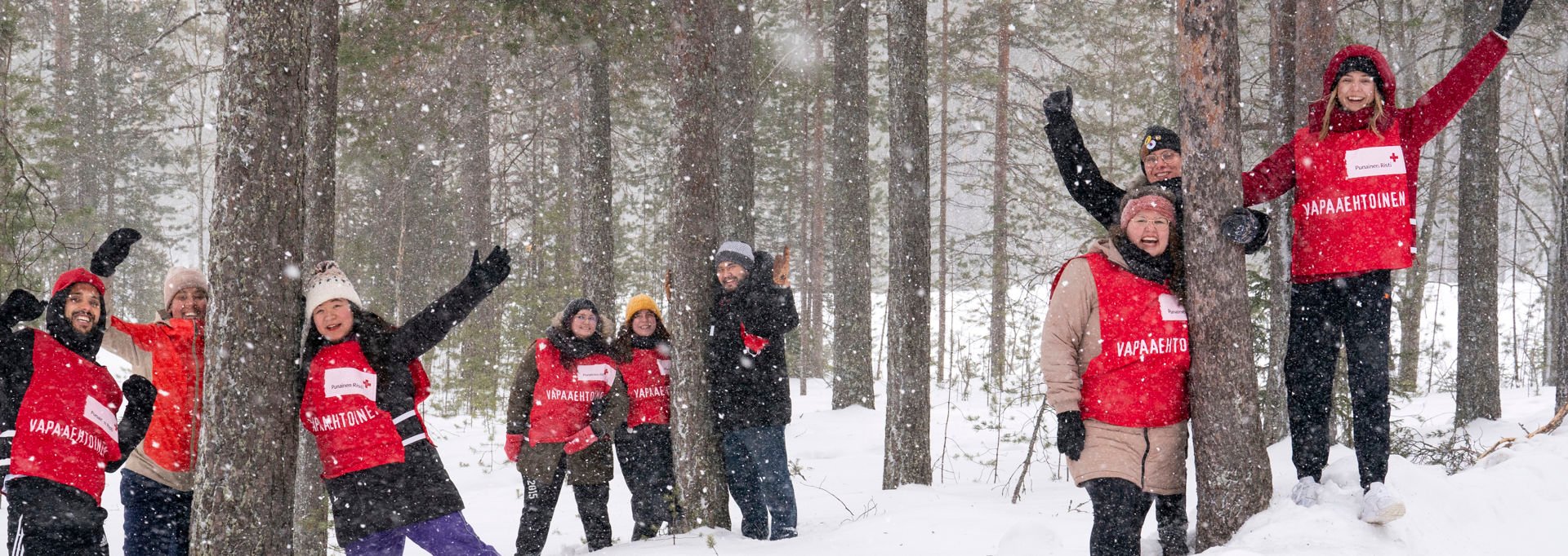 Punaisen Ristin vapaaehtoisia ulkona tapahtumassa; etualalla henkilö punaisessa liivissä ja taustalla muita vapaaehtoisia.