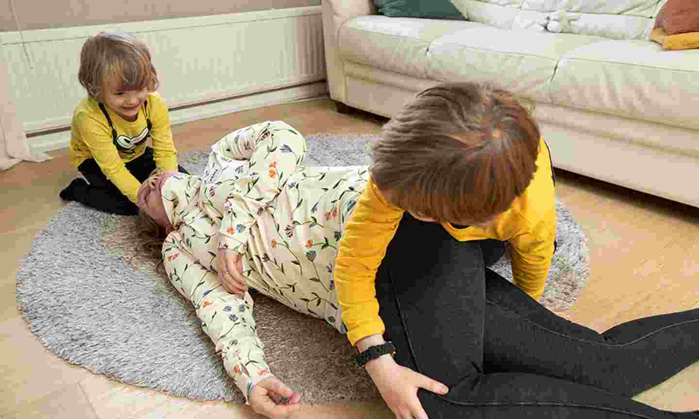 Leikki-ikäiset lapset harjoittelevat lattialla äidin kääntämistä kylkiasentoon.