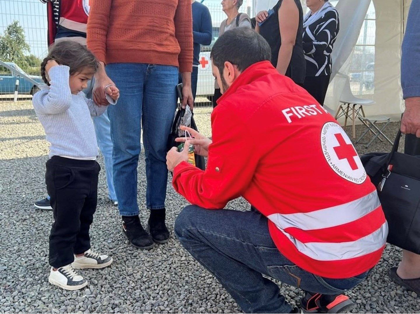 Vapaaehtoinen Armenian Punaisen Ristin takissa auttaa lasta.