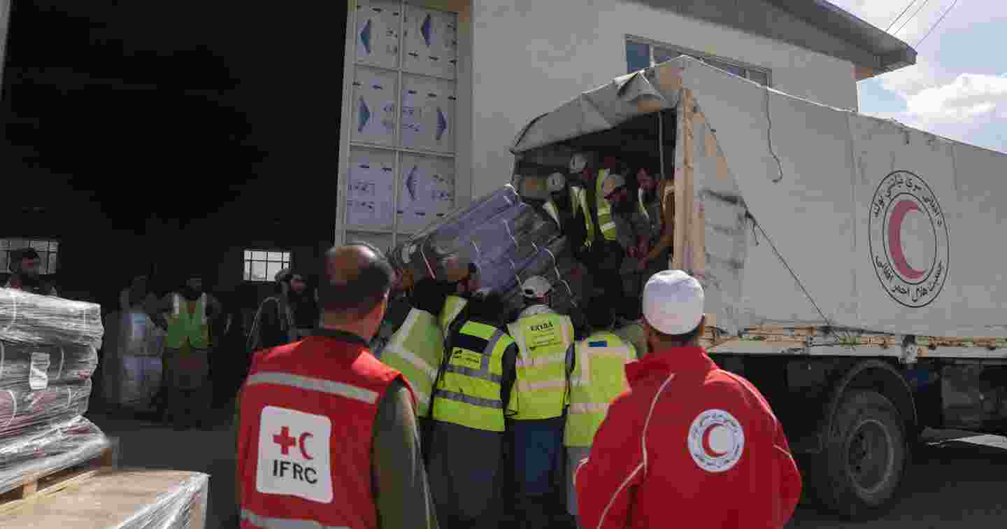 Henkilöt purkavat Afganistanin Punaisen Puolikuun rekka-autosta avustustarvikkeita.