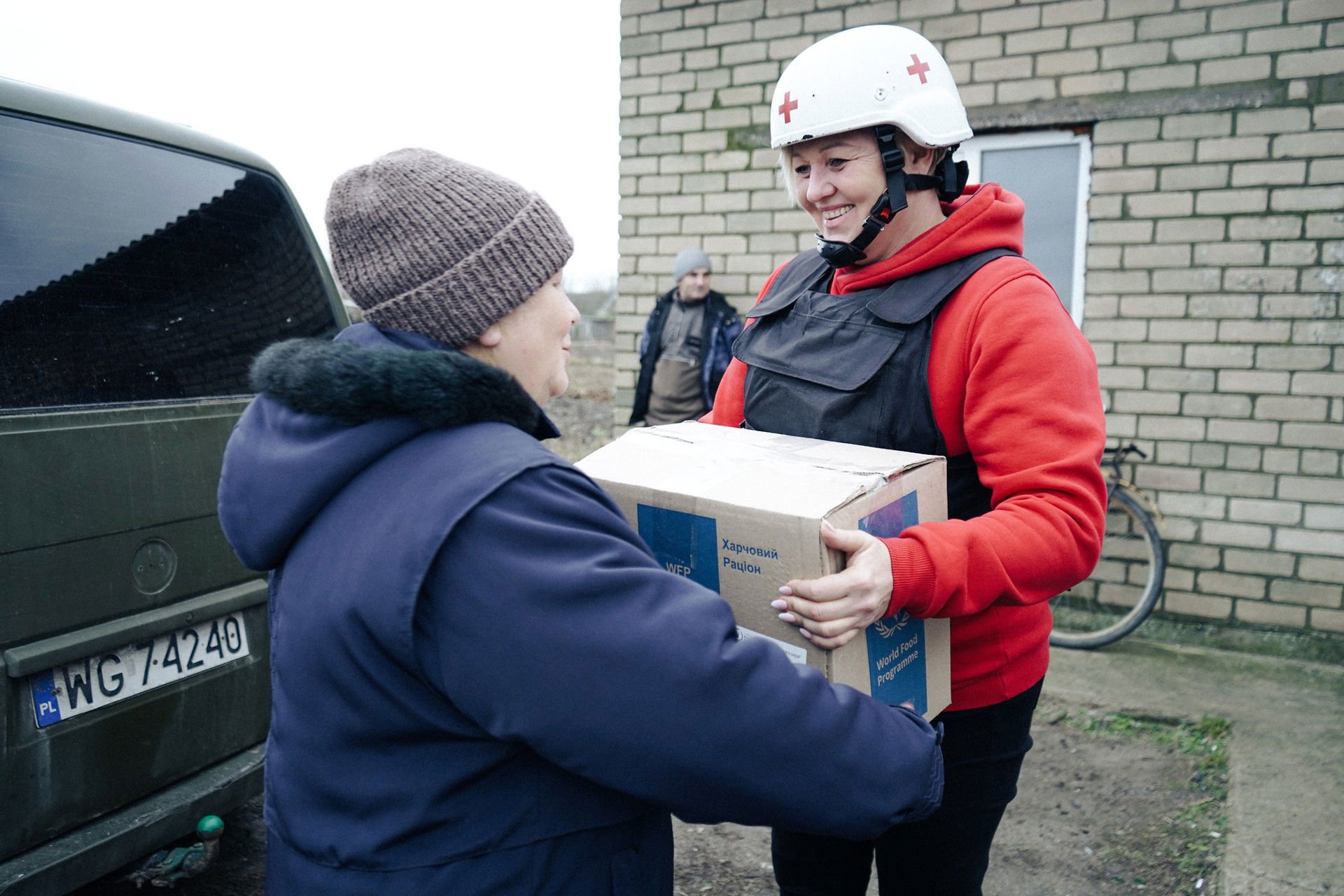 Punaisen Ristin tiimi jakaa avustustarvikkeita vanhemmalle ihmiselle