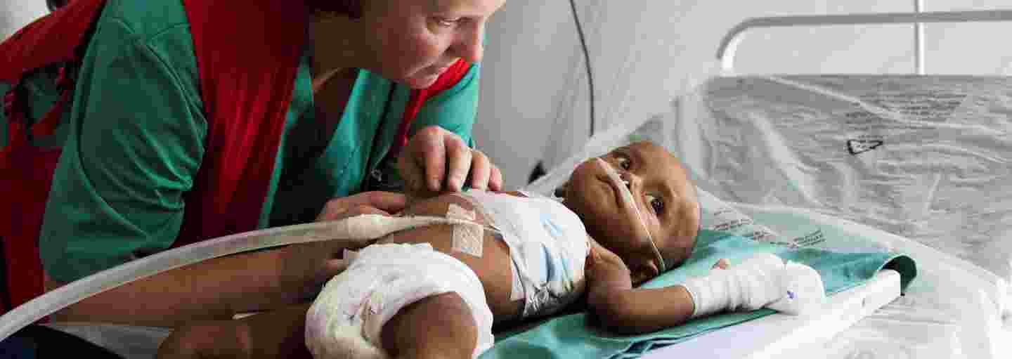 Punaisen Ristin avustustyöntekijä huolehtii vauvasta kenttäsairaalassa.