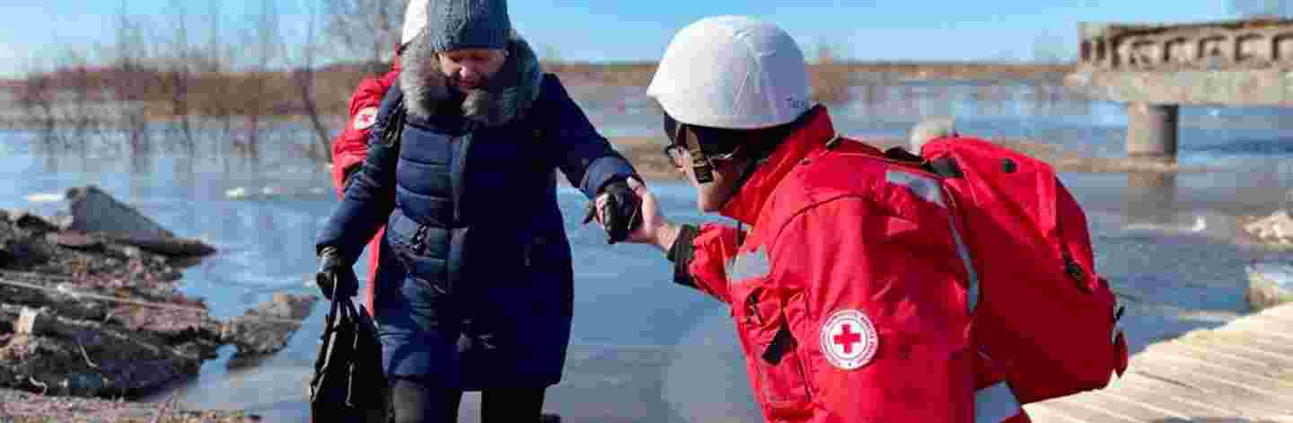 Ukrainan Punaisen Ristin vapaaehtoinen auttaa iäkästä henkilöä.