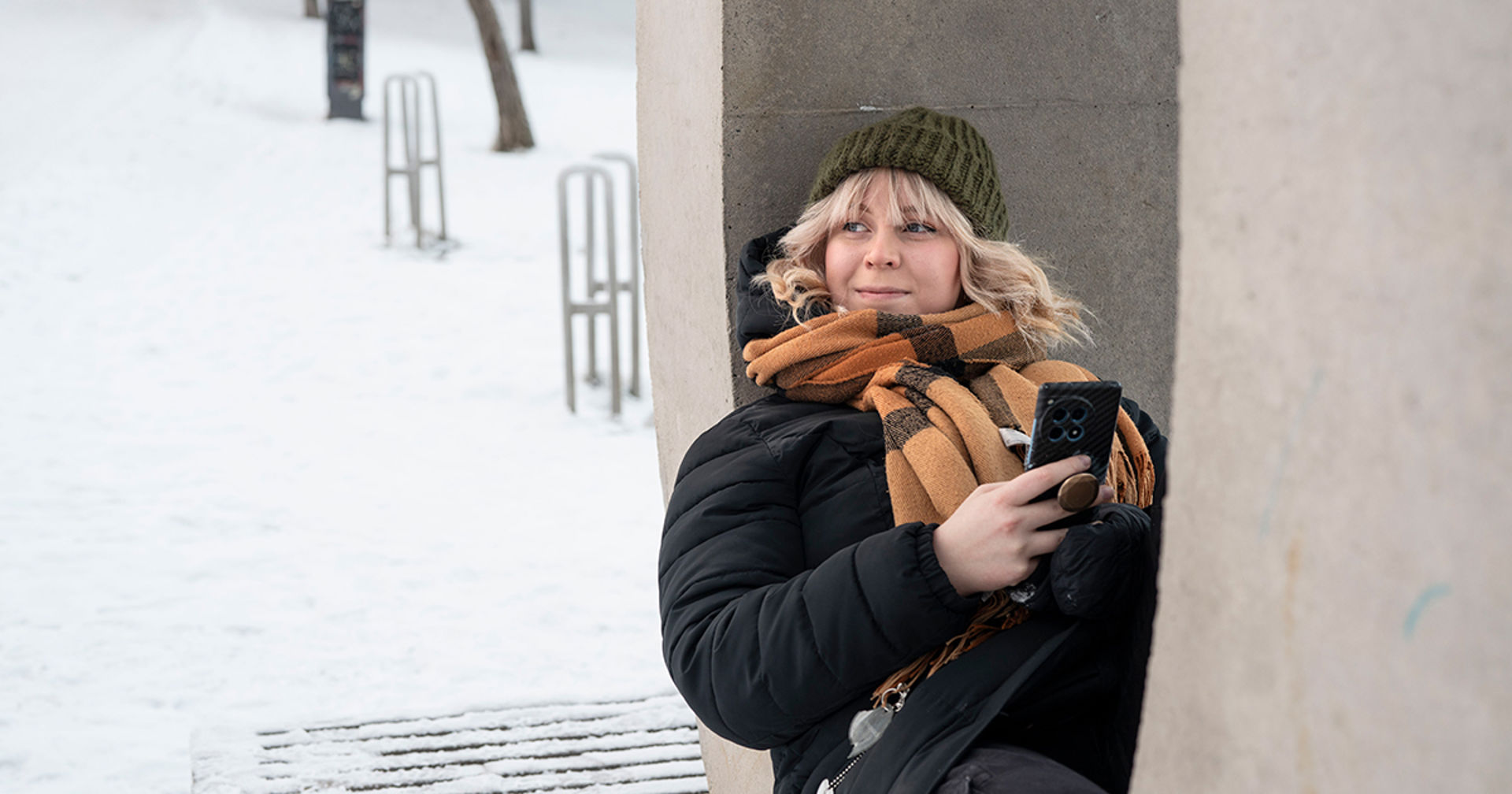 Vapaaehtoinen istuu ulkona puhelin kädessä ja hymyilee