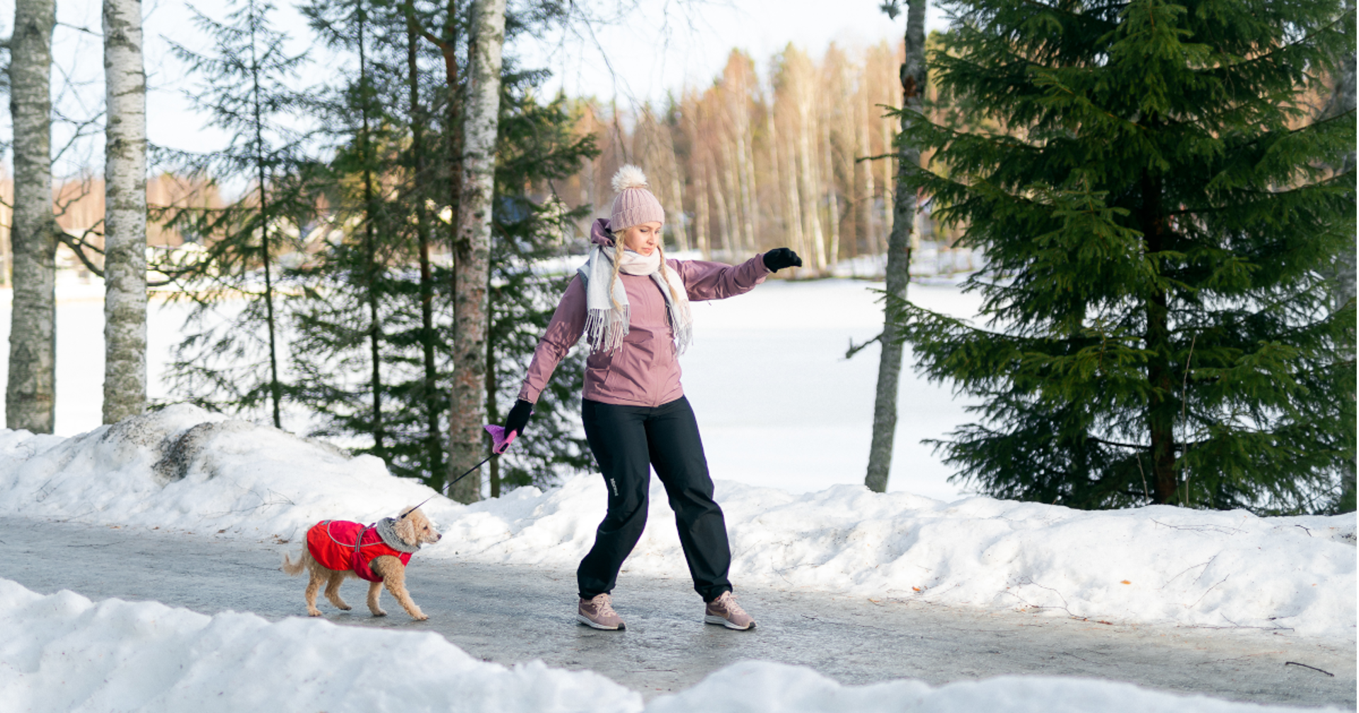 Henkilö kävelee koiransa kanssa liukkaalla ulkoilureitillä.