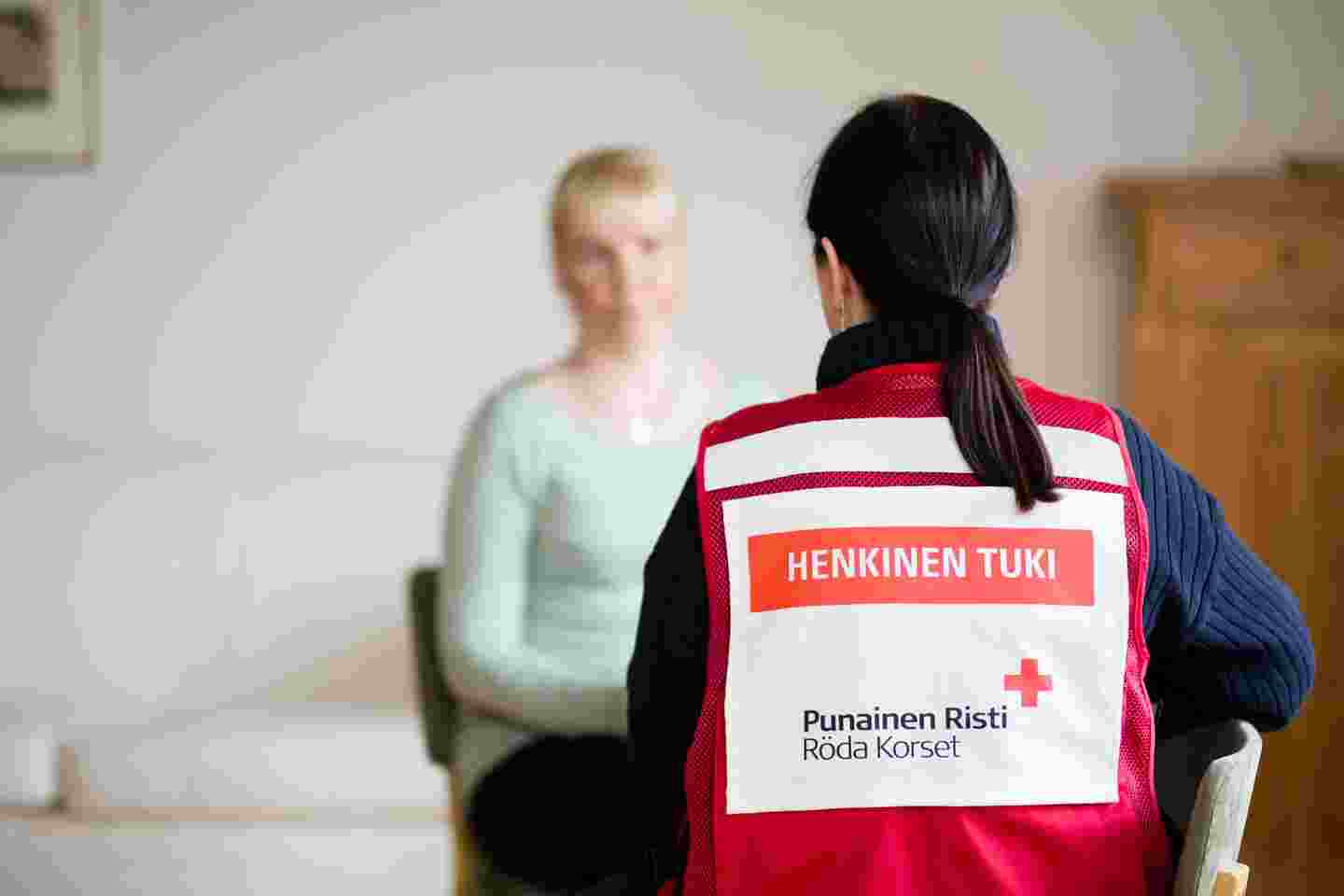 Henkilö Punaisen Ristin henkisen tuen vapaaehtoisliiveissä keskustelee toisen henkilön kanssa.