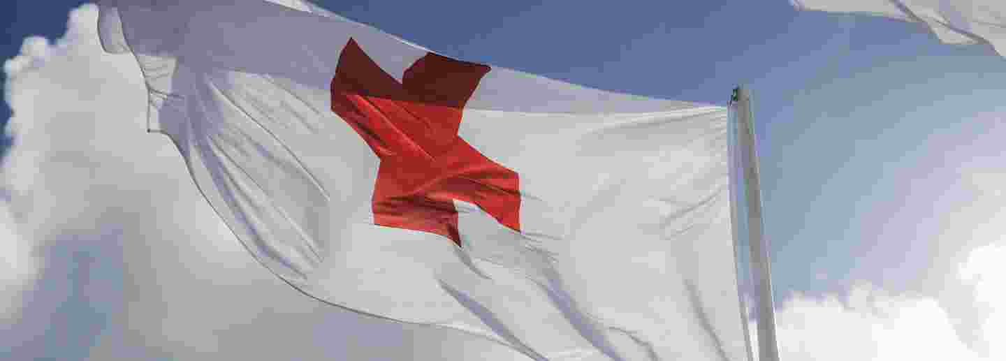 Punaisen Ristin lippu sinistä taivasta vasten.