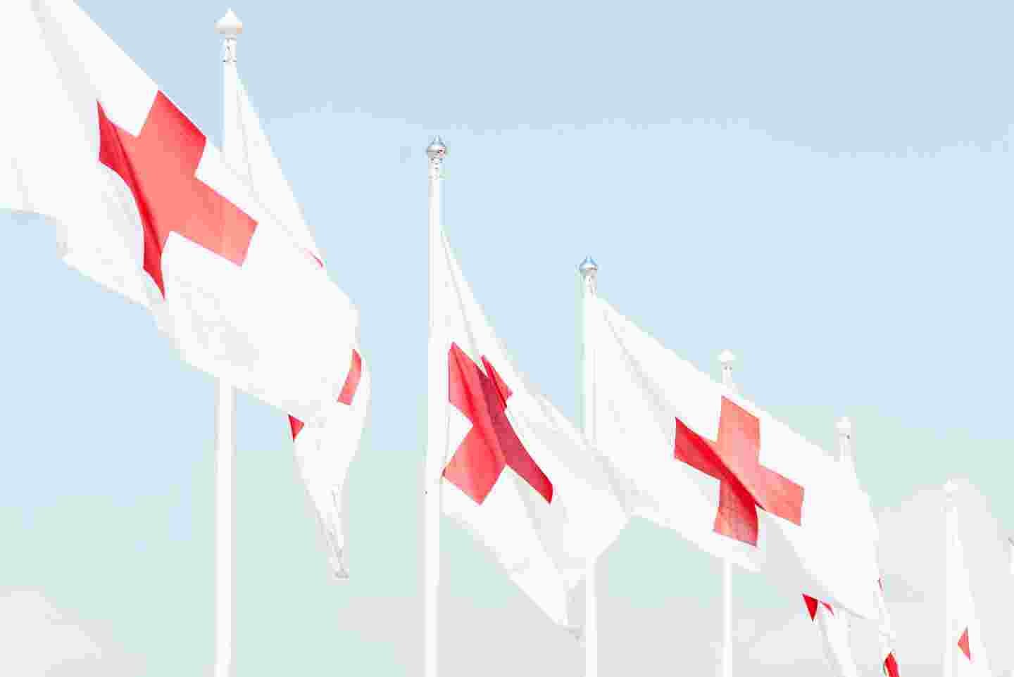 Punaisen Ristin lippuja sinistä taivasta vasten.