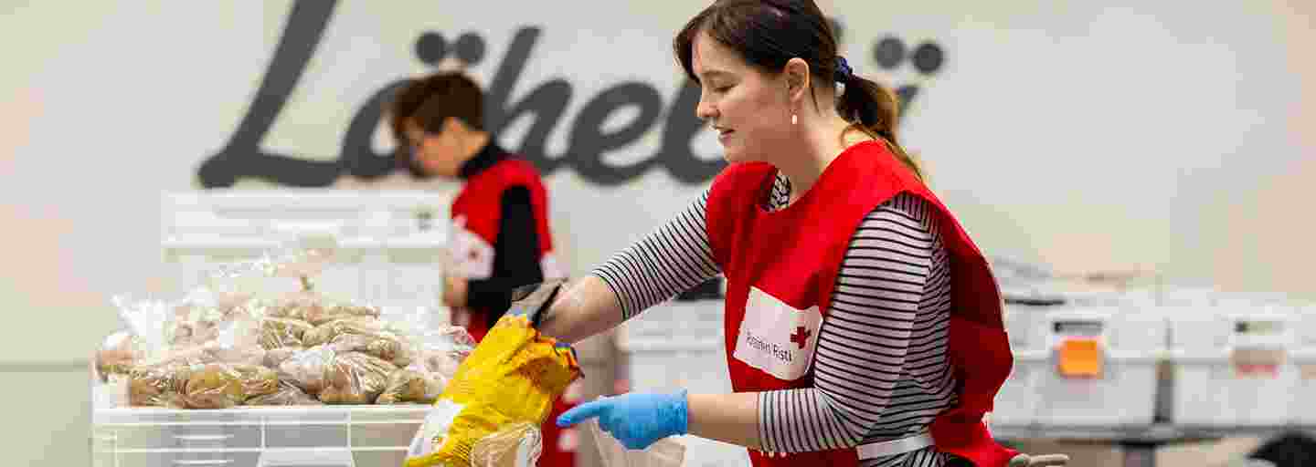 Kaksi Punaisen Ristin vapaaehtoista lajittelee ruoka-apua.